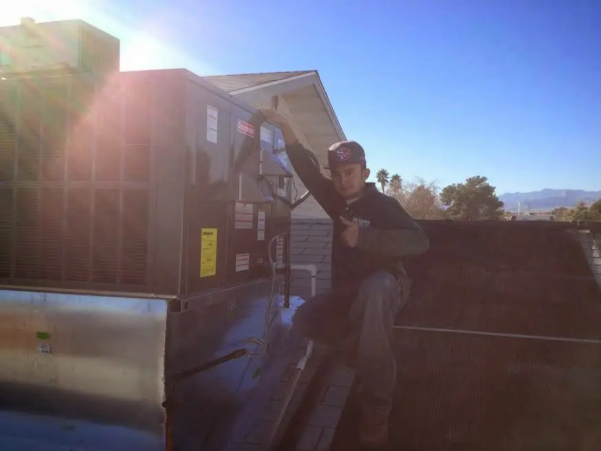 HVAC technician performing Air Duct Cleaning on a rooftop unit in Sanford